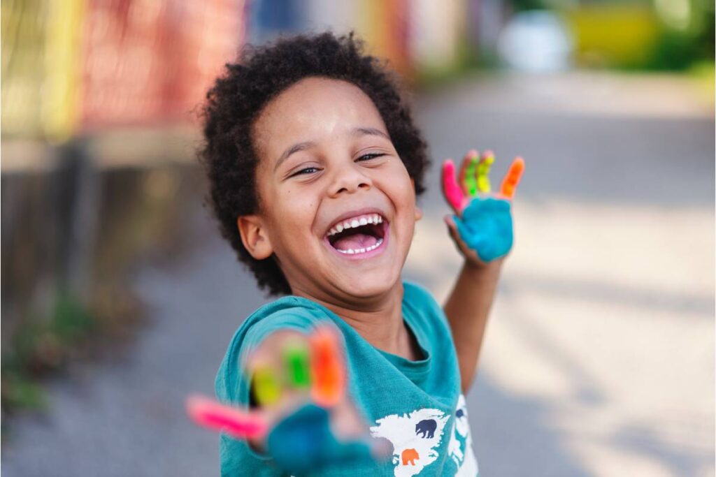 A child with paint on his hands smiles at the viewer near Lexington, Kentucky (KY)